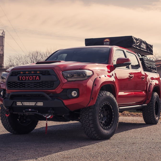 Angled red Tacoma sits on pavement displaying 25 degree sliders bolted in place
