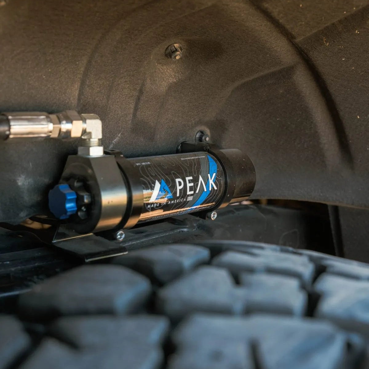 Close-up of a Peak brand air compressor attached to a vehicle tire.