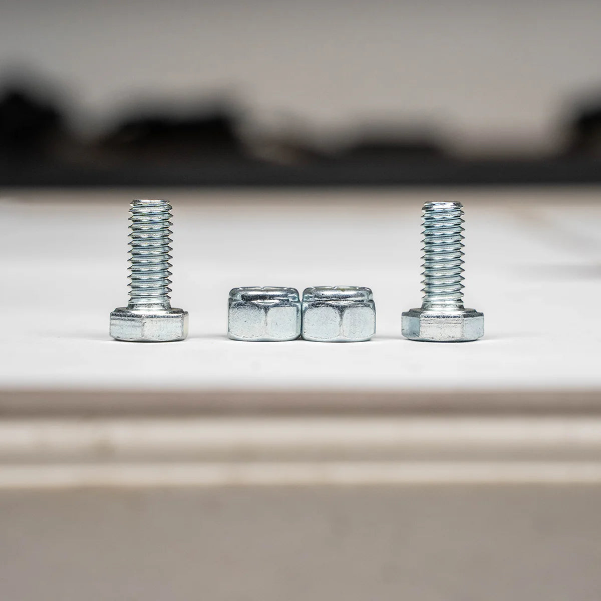 Two screws and two nuts on a blurred background