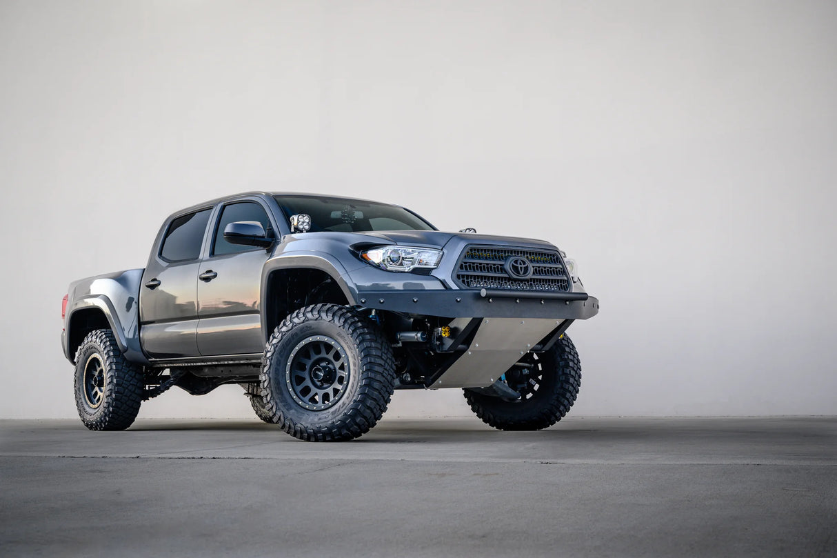 Silver Toyota truck with large off-road tires on a gray background