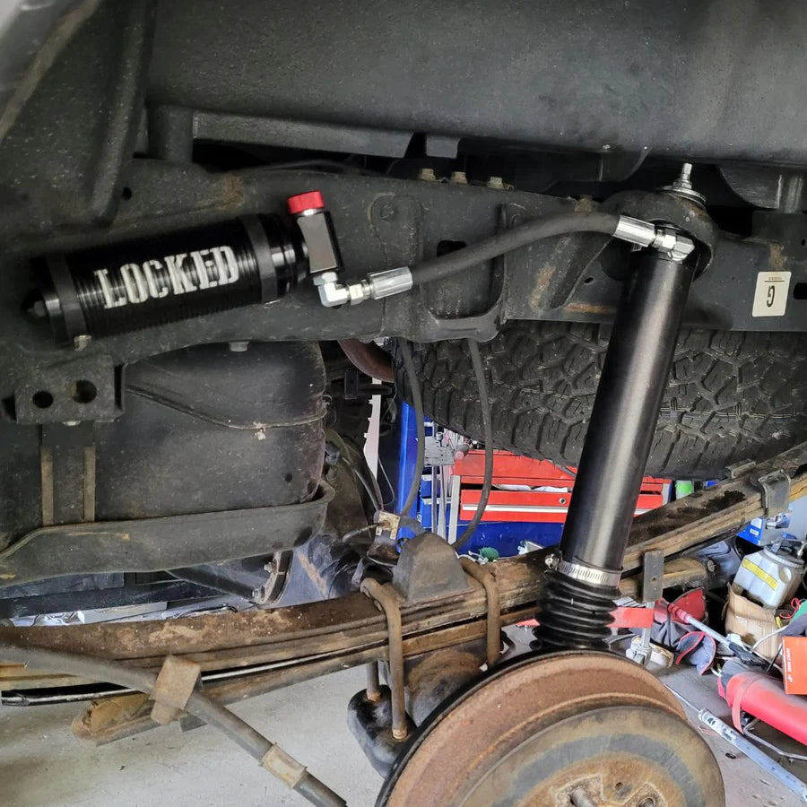 Close-up of a vehicle suspension system with a 'LOCKED' label on a workshop background.