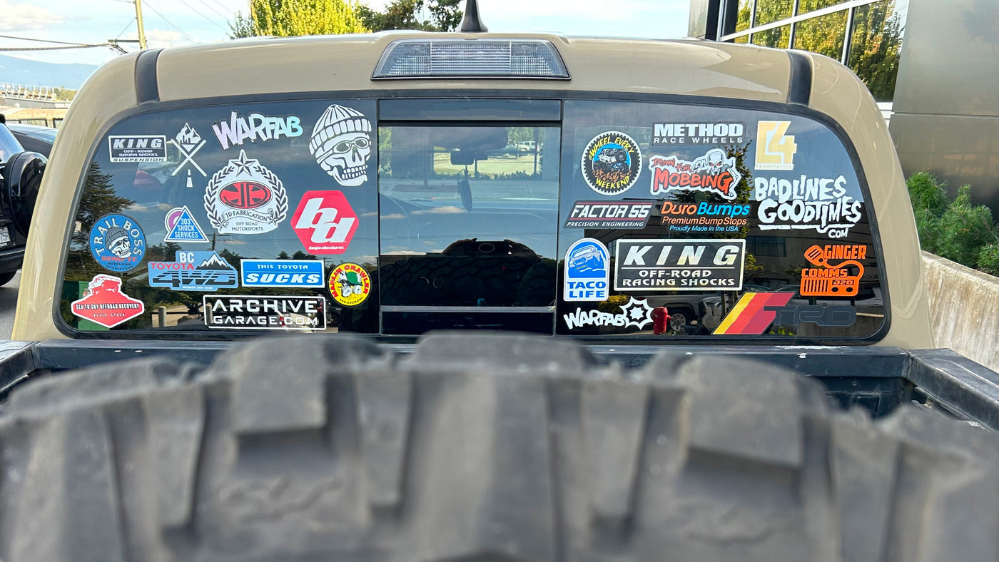 Back of a vehicle with various off road brand stickers on the windshield