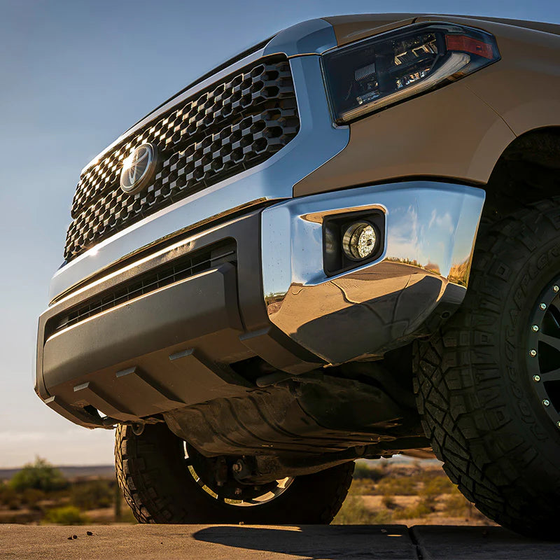 Close-up of a tundra's front grille and bumper with a clear sky background showing white fog lights
