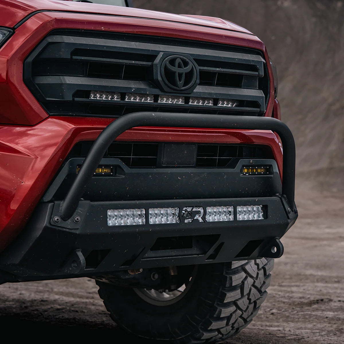 Red Tacoma with stealth bumper and bull bar on dirt road