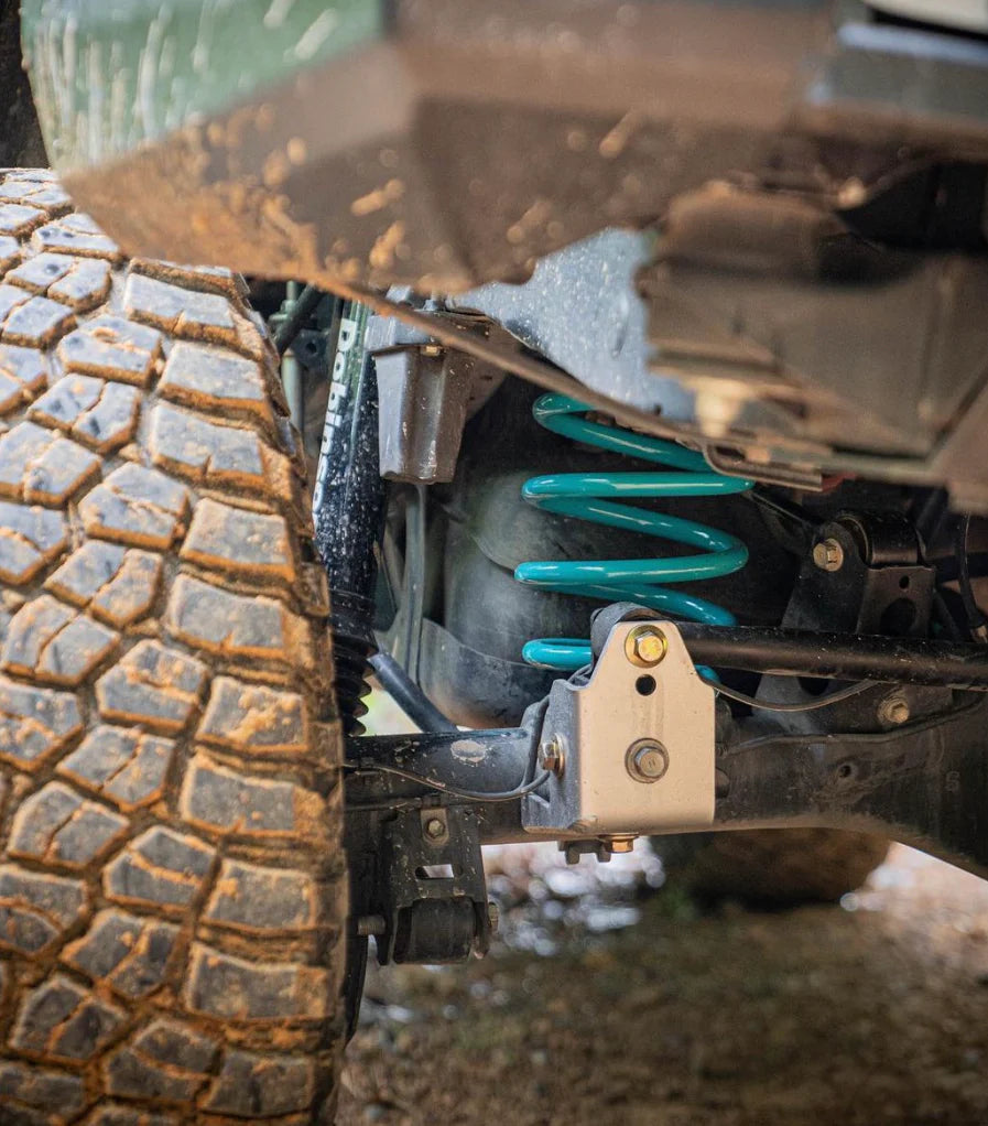 Close-up of a vehicle's suspension system with a tire on a rough terrain.