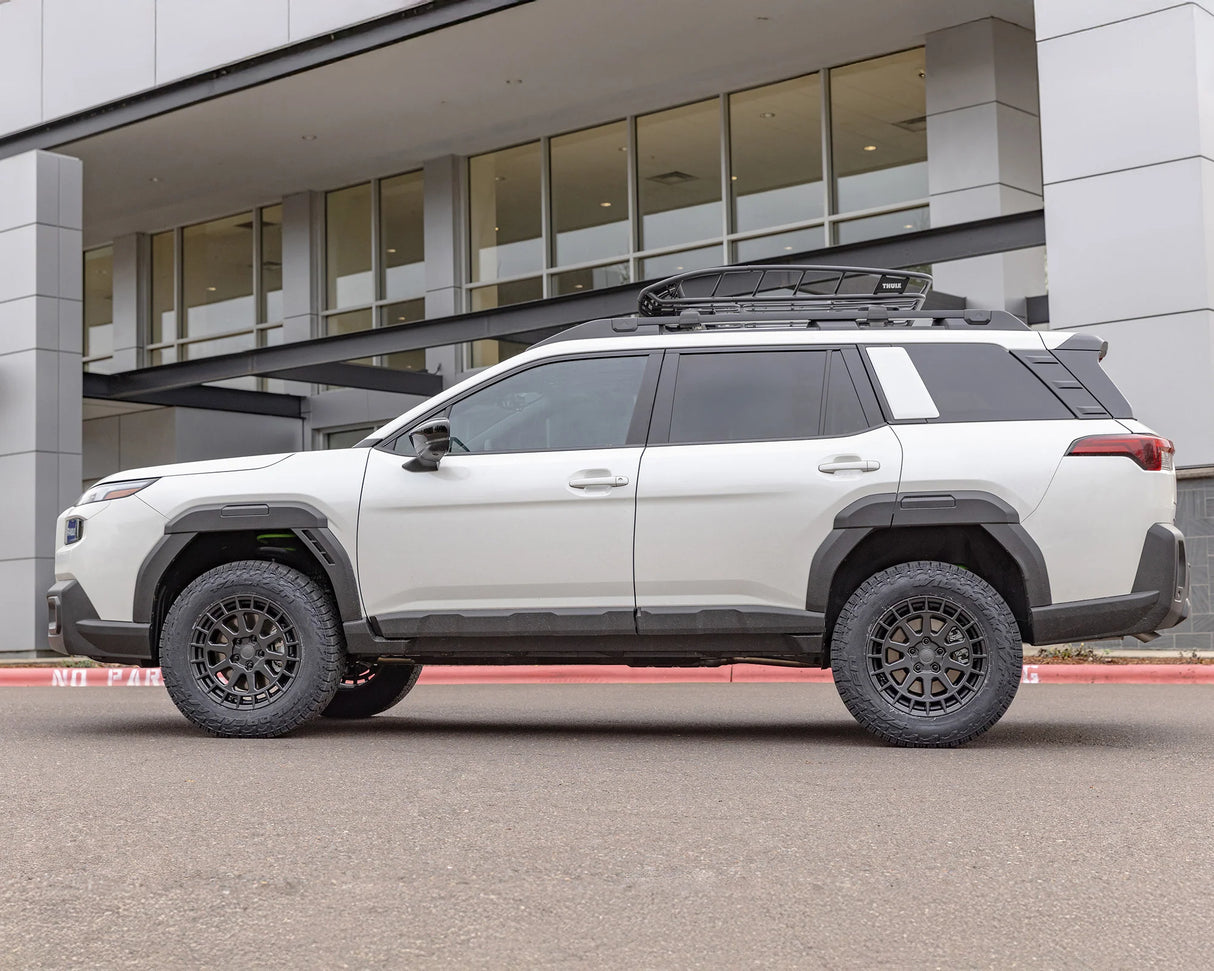 White SUV with roof rack parked in front of a modern building