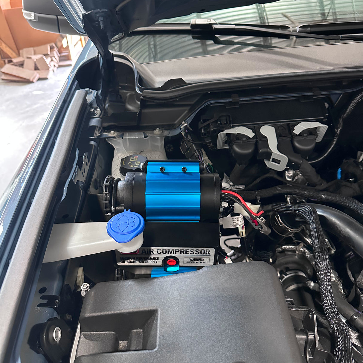 Air compressor installed in a vehicle's engine bay