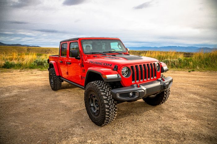 Red Jeep Gladiator Rubicon truck on a dirt road with a scenic background