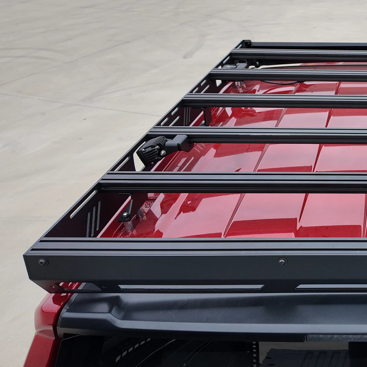 Black roof rack system on a red vehicle with a light gray background