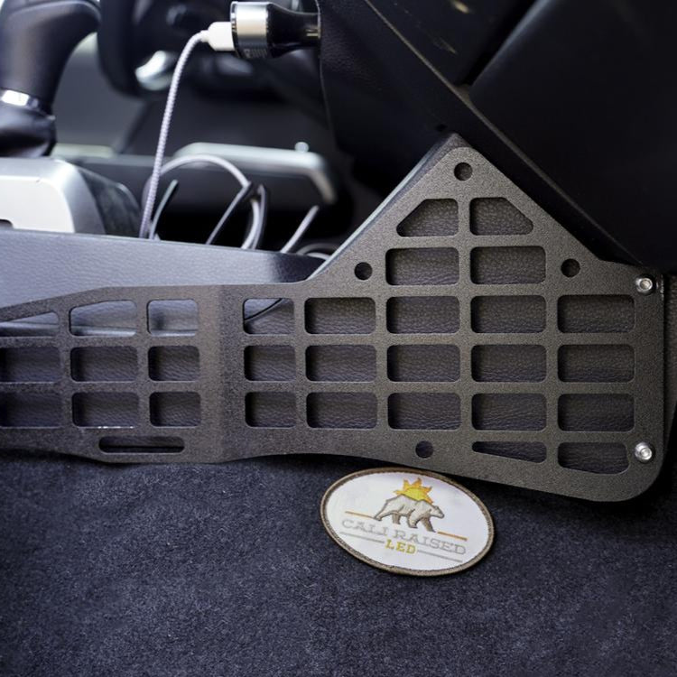 Black metal MOLLE panel on a car interior background