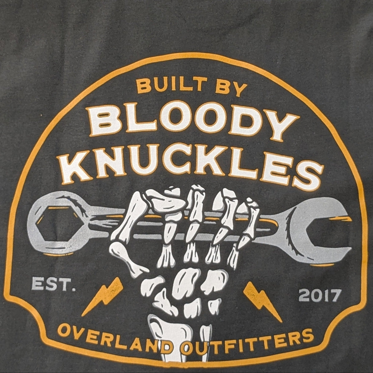 Close up of back graphic with skeleton hand clenching wrench