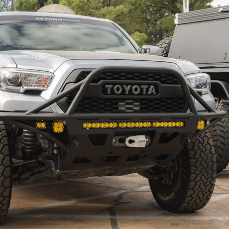 Silver Toyota truck with off-road bumper and lights in a parking lot.