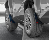 Close-up of a car's wheel arch with mud flaps on a road.
