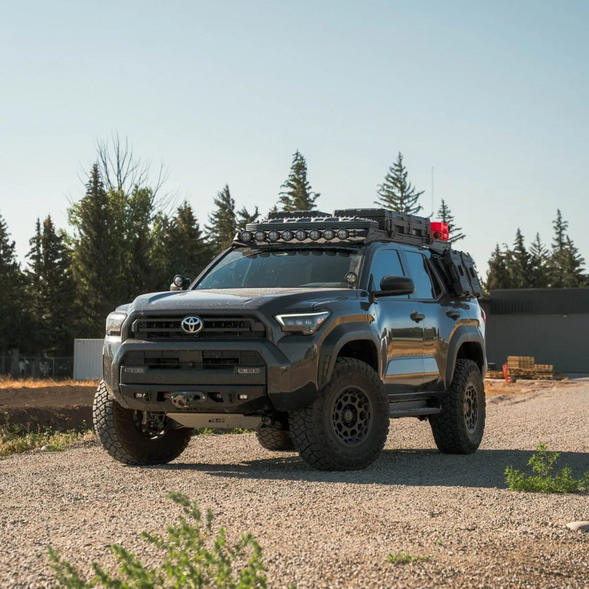 Toyota truck with off-road equipment on a gravel surface with trees in the background