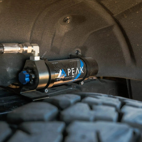 Close-up of a Peak brand air compressor attached to a vehicle tire.