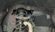 Close-up of a vehicle's undercarriage with suspension components and a black skid plate.