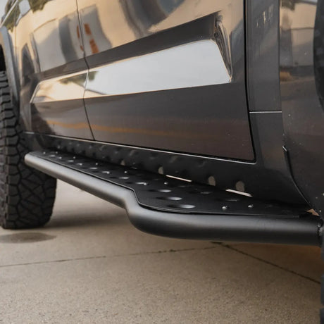 Close-up of a black vehicle's side step on a concrete surface