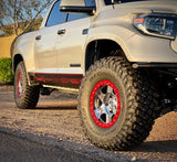 White truck with red rim and off-road tires on a road