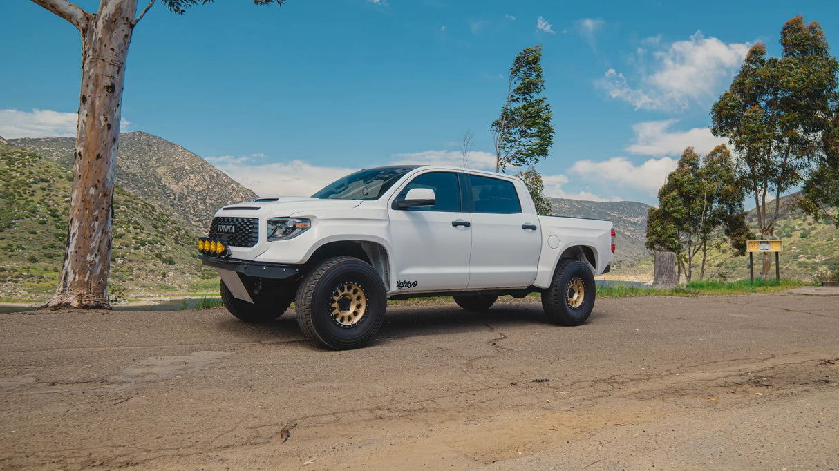 White off-road truck parked on a dirt road with a scenic background