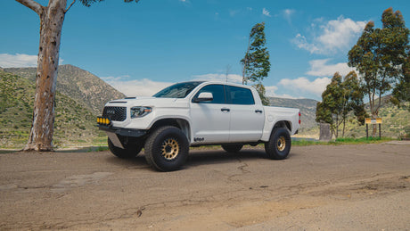 White off-road truck parked on a dirt road with a scenic background
