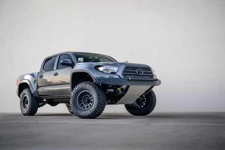 Silver Toyota truck with large off-road tires on a gray background