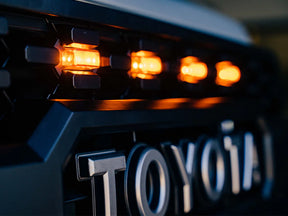 Close-up of a Toyota vehicle with illuminated amber lights on a dark background