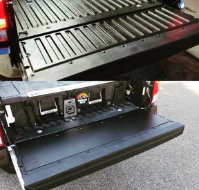 A black plastic tailgate insert for a Toyota Tacoma, displayed in an installed position on the truck's bed.