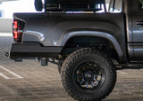 Close-up of a gray truck with a black tire and wheel on a parking lot.