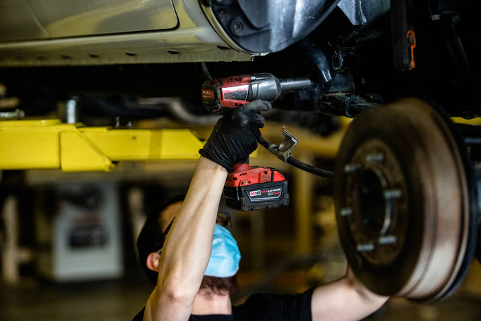 Mechanic working on a car tire with a tool in a garage setting