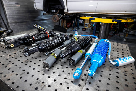 Collection of shock absorbers on a metal workbench in a garage setting