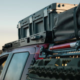 Roof rack system on a vehicle with storage boxes attached against a clear sky.