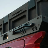 Close-up of a vehicle roof rack system on a red vehicle with a clear sky background.