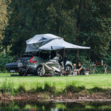 Car with a rooftop tent near a lake and trees