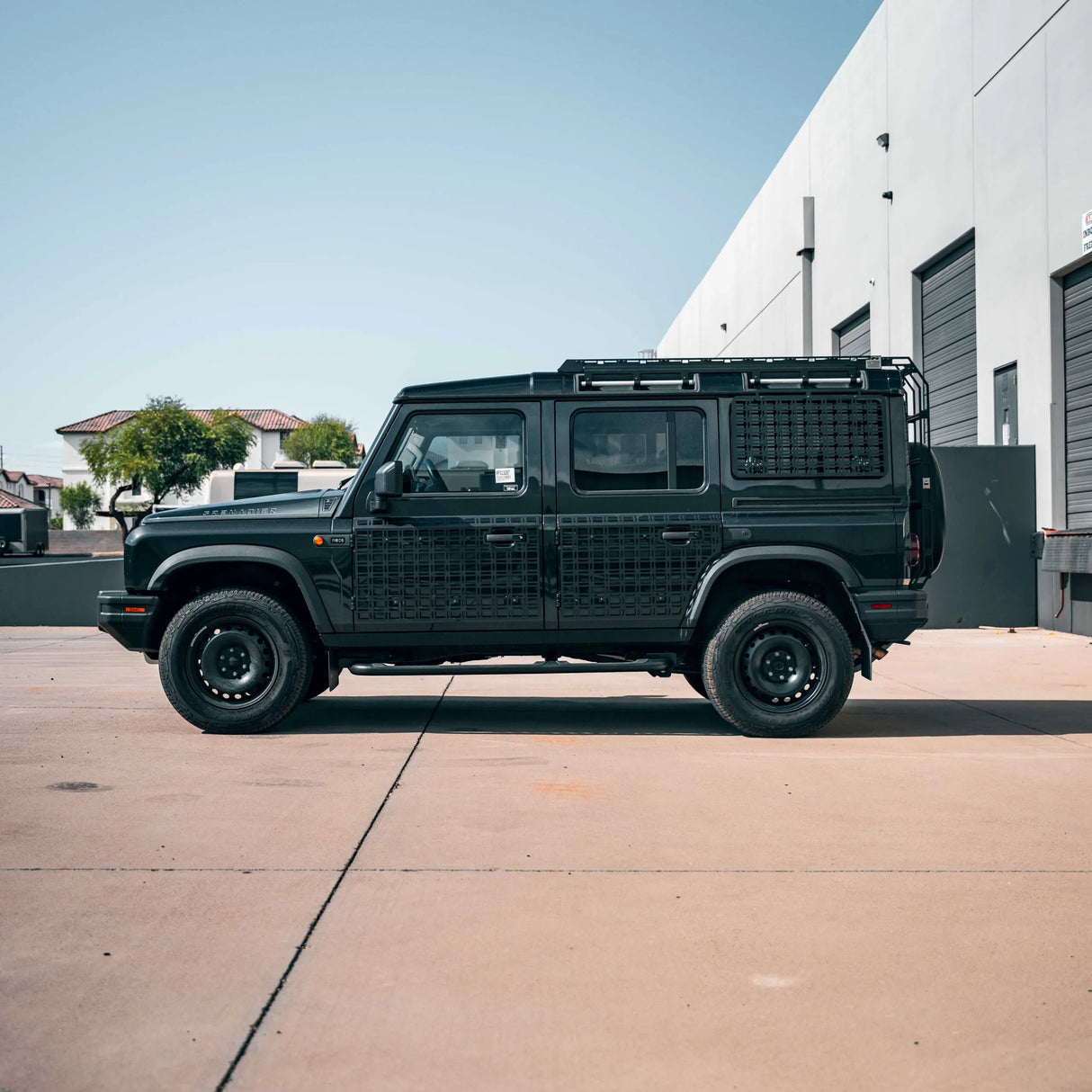 Black off-road vehicle parked on a concrete surface with a building in the background