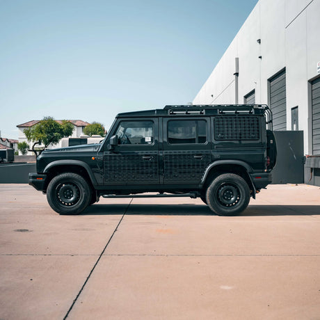 Black off-road vehicle parked on a concrete surface with a building in the background