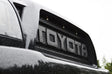 Close-up of a Toyota logo on a vehicle grille with raindrops.