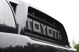 Close-up of a Toyota logo on a vehicle grille with raindrops.