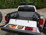 Truck bed with storage compartments and equipment, surrounded by trees.