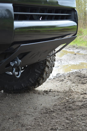Close-up of a vehicle's front bumper and tire on a muddy road