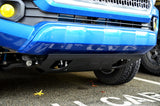 Close-up of a blue vehicle's front bumper with a visible license plate area.