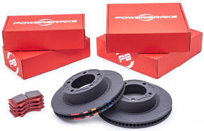 A set of PowerBrake D-Line front brake rotors and pads, including two rotors with slotted patterns and two sets of PB05 compound brake pads, alongside their red packaging boxes.