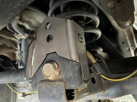 Close-up of a mechanical component with rust and wear on a vehicle's undercarriage.