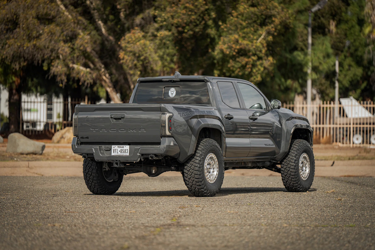 Black pickup truck on a road with trees and a fence in the background