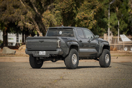 Black pickup truck on a road with trees and a fence in the background