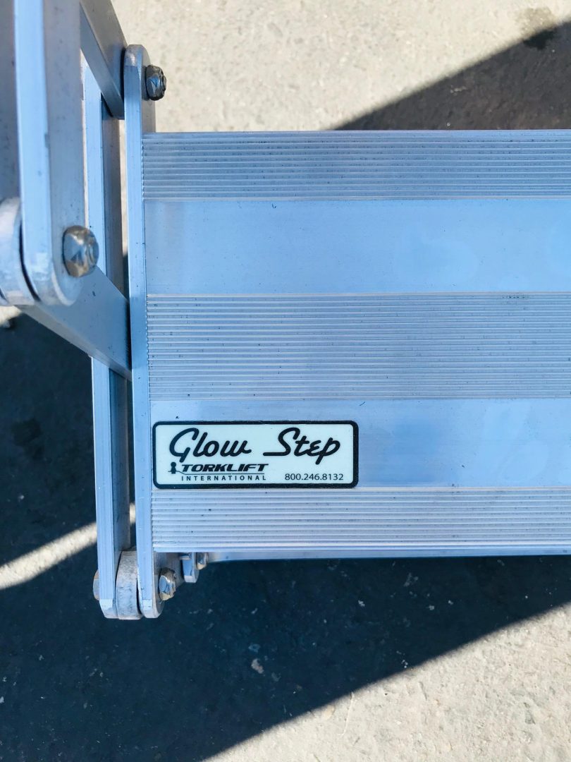 Metal step ladder with 'Glow Step' branding on a concrete surface