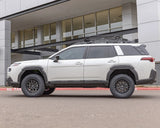 White SUV with roof rack parked in front of a modern building