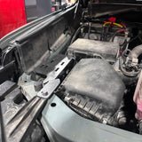 Car engine compartment with visible components and wiring.