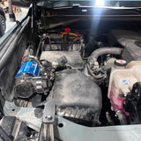 Car engine compartment with visible components and wiring of a mounted air compressor.