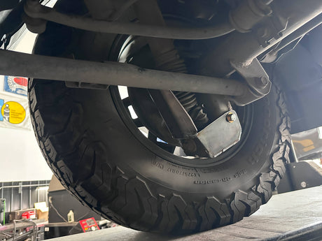 Close-up of a tire and suspension system on a vehicle.