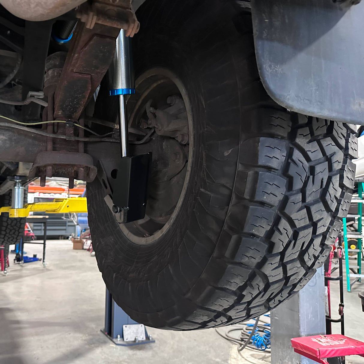 Close-up of a vehicle tire and suspension system in a garagesetting.